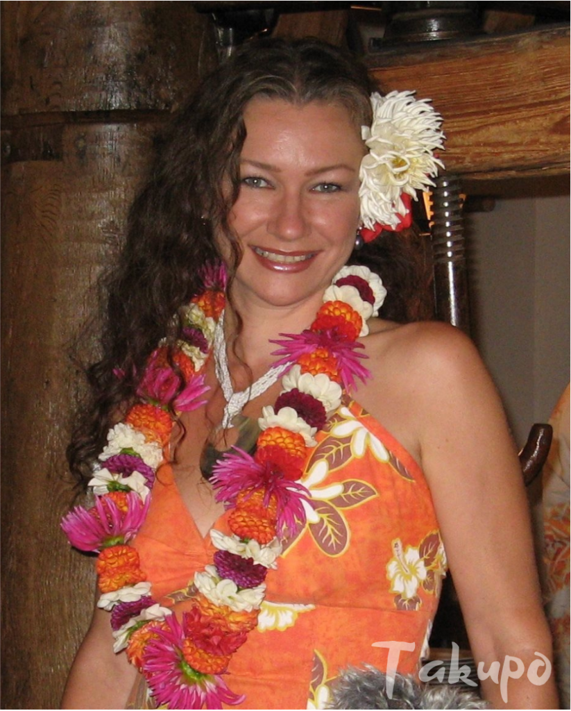 Katrin Lenz in orangefarbenem Kleid mit Blumenlei aus frischen Blüten